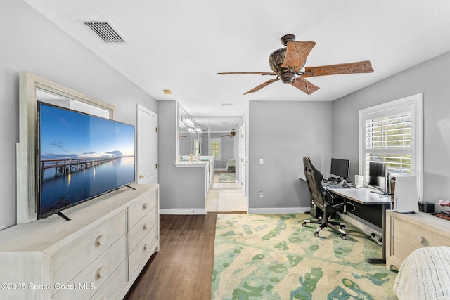 office area with dark wood finished floors, visible vents, plenty of natural light, and a ceiling fan