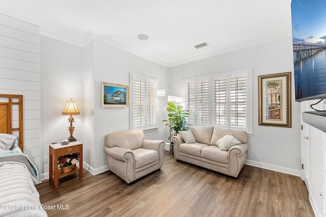 living room with plenty of natural light, crown molding, visible vents, and wood finished floors