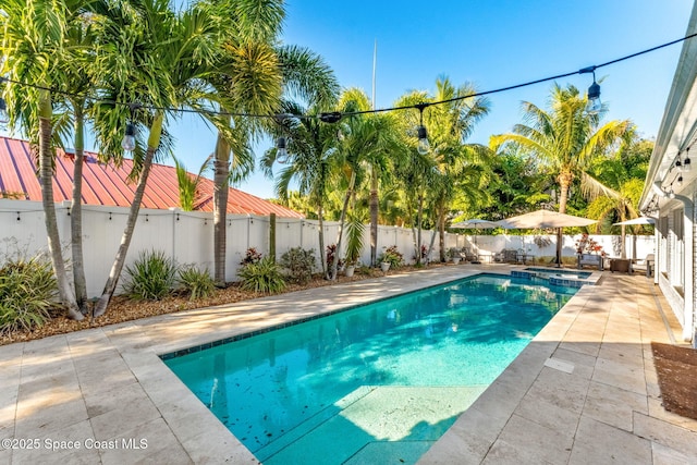 view of pool featuring a patio, a fenced backyard, and a pool with connected hot tub