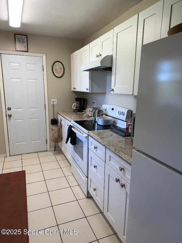 kitchen with light tile patterned floors, freestanding refrigerator, range with electric cooktop, white cabinets, and under cabinet range hood