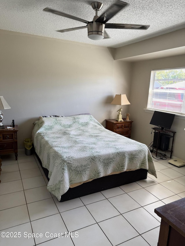 bedroom featuring light tile patterned floors, a ceiling fan, and a textured ceiling