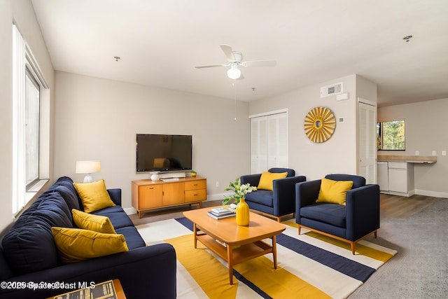 living area with visible vents, a ceiling fan, and baseboards