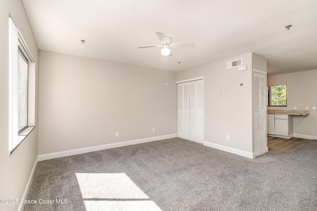 unfurnished bedroom with baseboards, carpet floors, visible vents, and ceiling fan