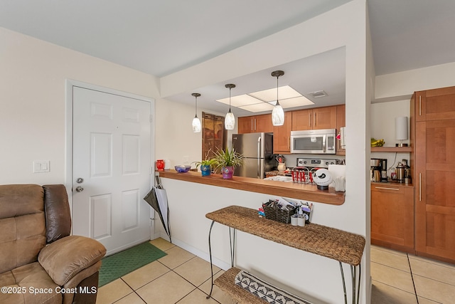 kitchen with visible vents, decorative light fixtures, open floor plan, light tile patterned floors, and appliances with stainless steel finishes