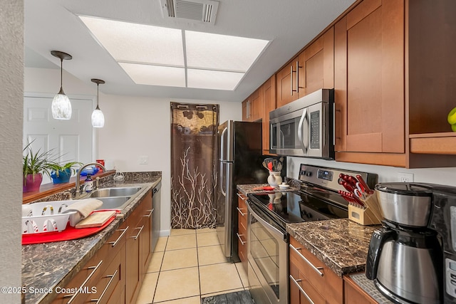 kitchen featuring visible vents, brown cabinets, a sink, appliances with stainless steel finishes, and light tile patterned flooring