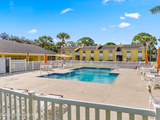 community pool featuring a patio, fence, and a residential view