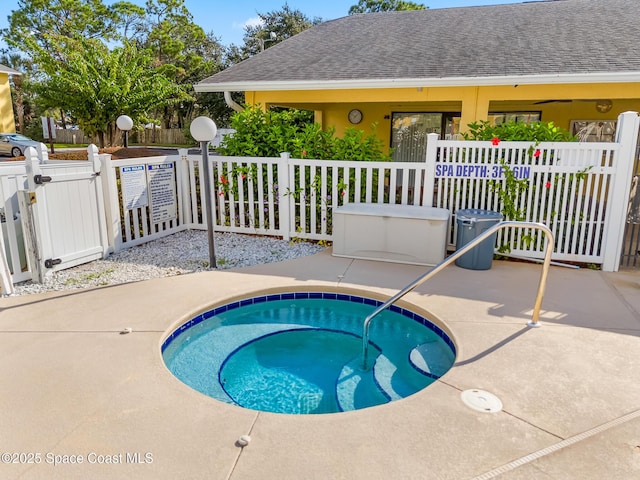 view of swimming pool featuring a gate, fence, and a hot tub