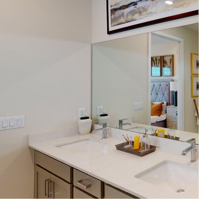 ensuite bathroom with double vanity, connected bathroom, and a sink