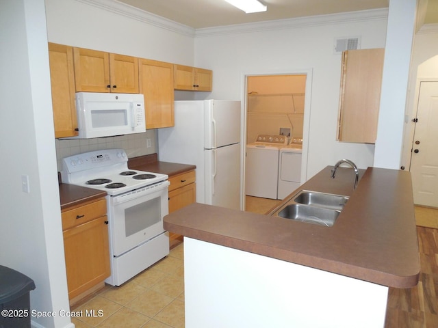 kitchen featuring ornamental molding, a peninsula, washer and dryer, white appliances, and a sink