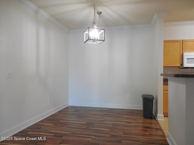 unfurnished dining area with dark wood finished floors, baseboards, and ornamental molding