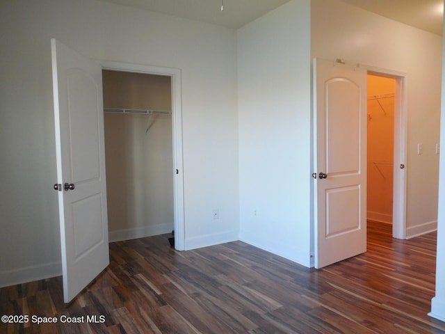 unfurnished bedroom featuring a closet, baseboards, and dark wood-style floors