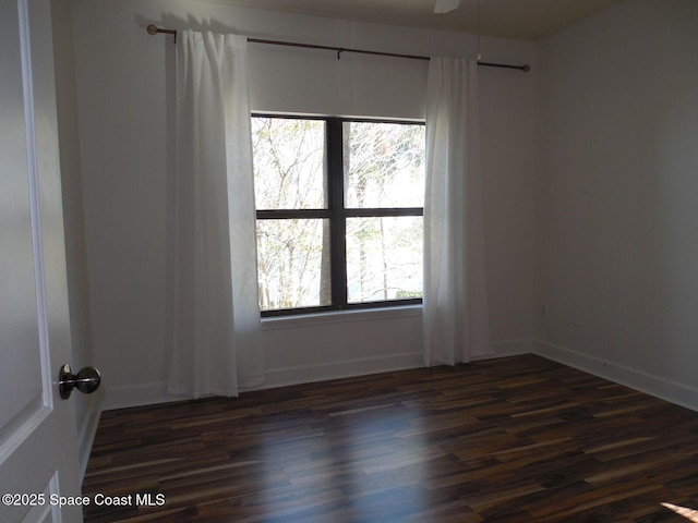 spare room with baseboards and dark wood-style floors