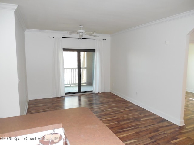 empty room featuring wood finished floors, baseboards, arched walkways, ceiling fan, and crown molding