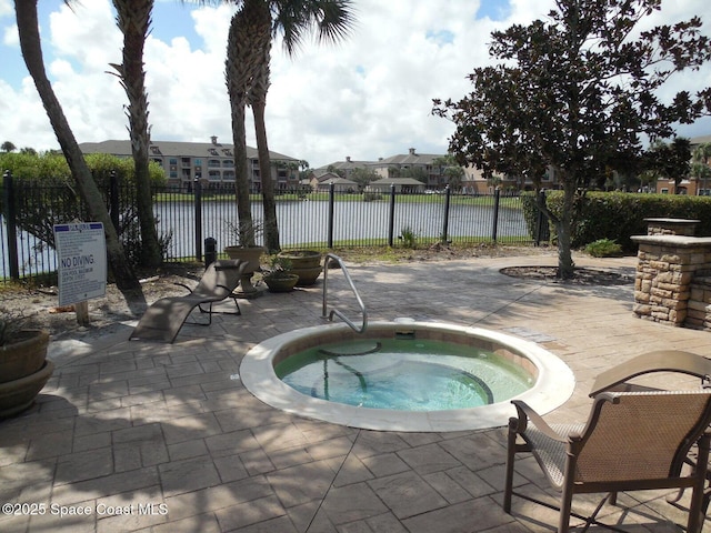 view of swimming pool featuring a patio area, a hot tub, a water view, and fence