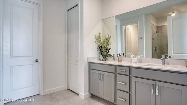 full bath featuring double vanity, baseboards, a stall shower, and a sink