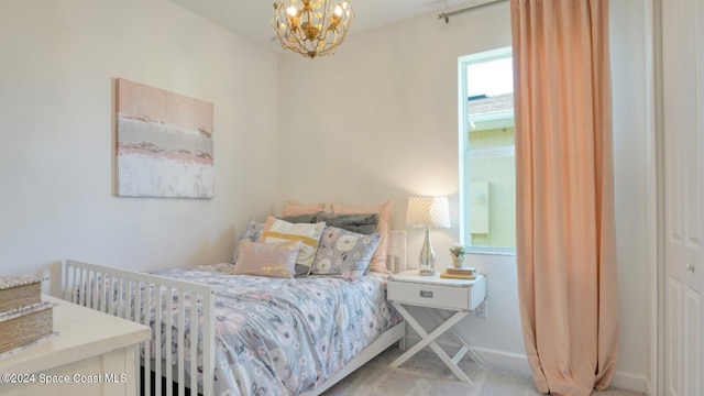 carpeted bedroom featuring an inviting chandelier and baseboards