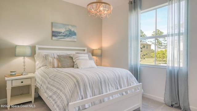 bedroom with baseboards, carpet, and a chandelier