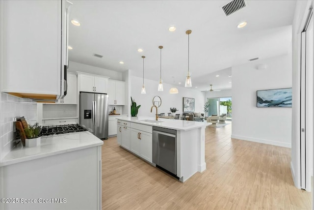 kitchen featuring a sink, open floor plan, visible vents, white cabinetry, and appliances with stainless steel finishes