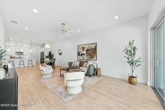 living room with light wood-type flooring, a ceiling fan, visible vents, and recessed lighting
