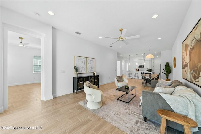 living area featuring recessed lighting, visible vents, a ceiling fan, baseboards, and light wood-style flooring