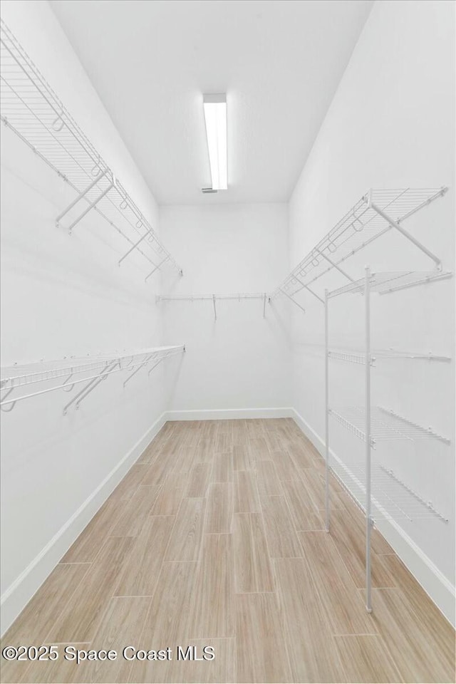 walk in closet with wood finished floors
