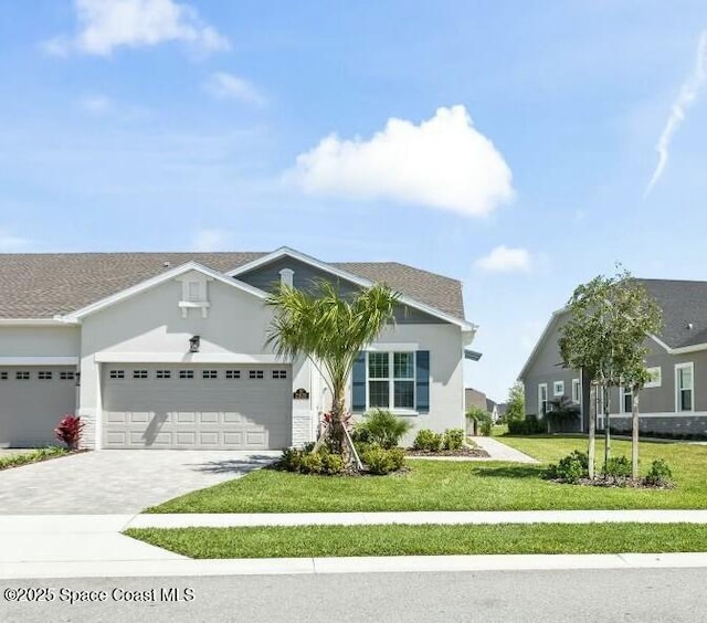 view of front of property featuring stucco siding, driveway, an attached garage, and a front lawn