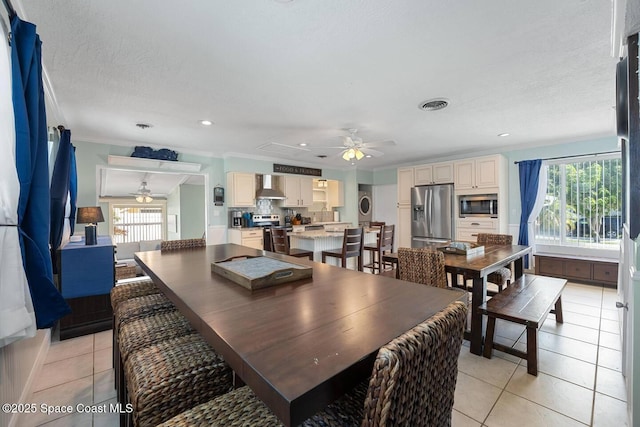 dining room with light tile patterned floors, visible vents, ceiling fan, and crown molding