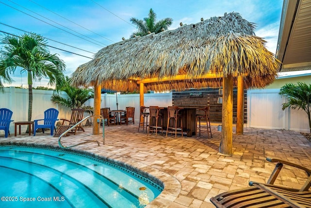 view of pool featuring a patio, a fenced backyard, and outdoor dry bar