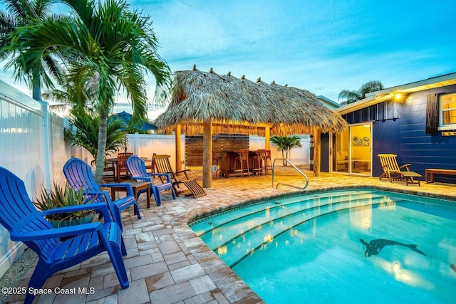 view of swimming pool featuring fence, outdoor dry bar, and a patio area