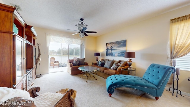 living room featuring ceiling fan, a healthy amount of sunlight, visible vents, and a textured ceiling