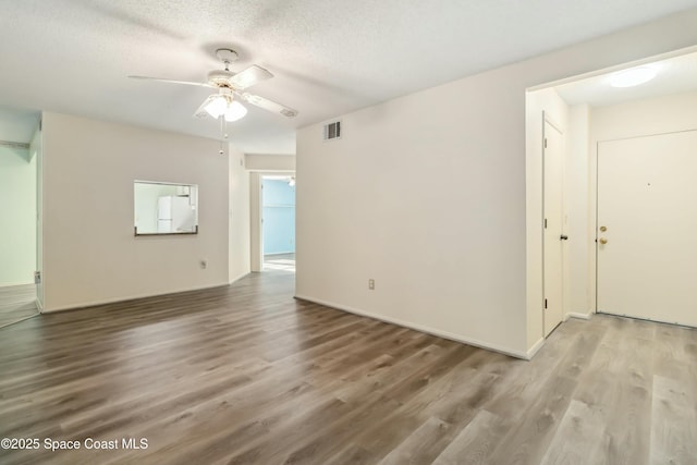 unfurnished living room with visible vents, baseboards, ceiling fan, wood finished floors, and a textured ceiling