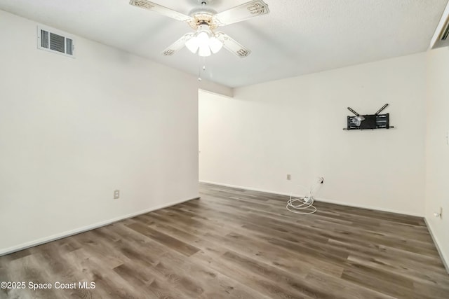 empty room featuring baseboards, wood finished floors, visible vents, and ceiling fan