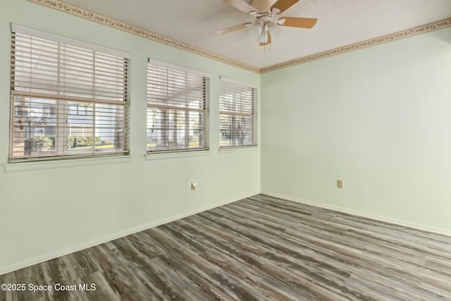 spare room with baseboards, wood finished floors, and a ceiling fan