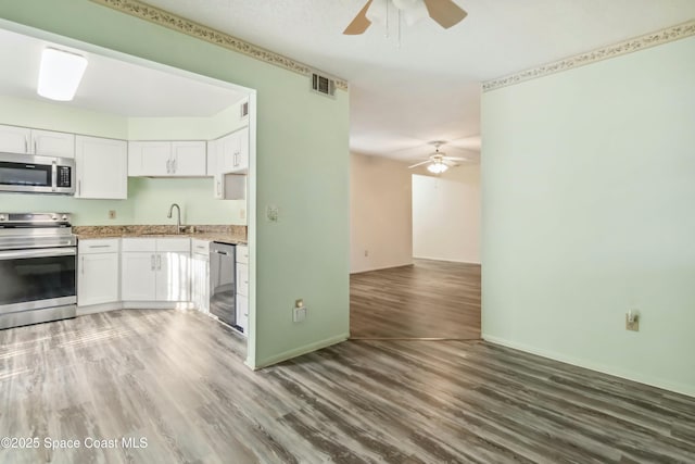 kitchen featuring visible vents, light wood-type flooring, white cabinets, stainless steel appliances, and a sink