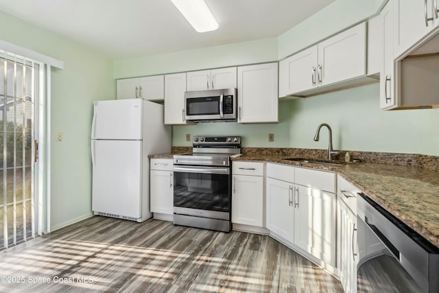 kitchen featuring dark stone countertops, dark wood-style flooring, a sink, stainless steel appliances, and white cabinets