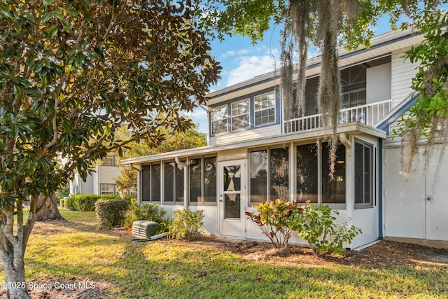 rear view of house with a yard and a sunroom