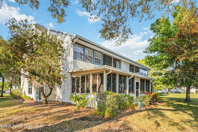 rear view of property featuring a lawn and a sunroom