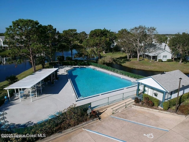 community pool featuring a water view and fence