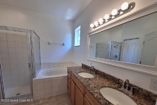 bathroom featuring a shower stall, a textured ceiling, a garden tub, and a sink