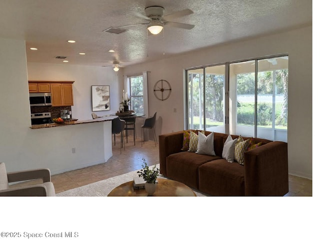 living room with light tile patterned floors, recessed lighting, a textured ceiling, and ceiling fan