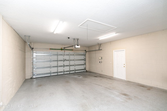 garage featuring concrete block wall and a garage door opener