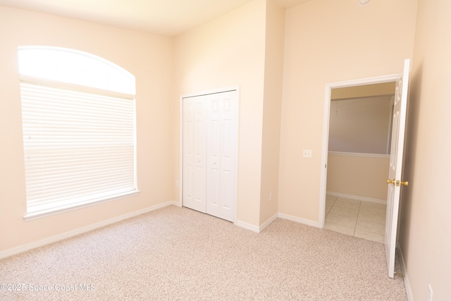 unfurnished bedroom with a closet, baseboards, and carpet flooring