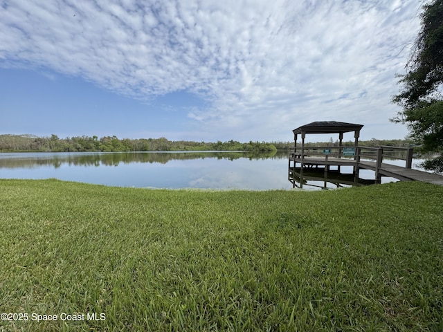 view of dock with a gazebo, a lawn, and a water view