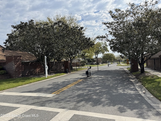 view of street featuring curbs, a gated entry, and a gate