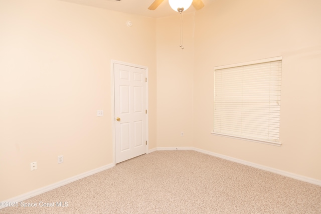 carpeted empty room featuring high vaulted ceiling, baseboards, and ceiling fan