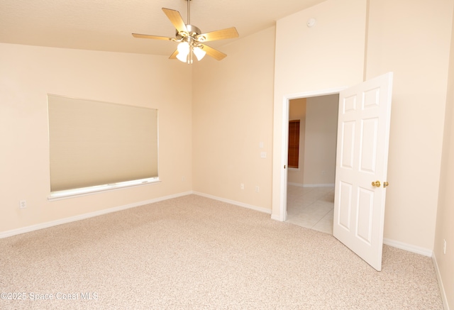 carpeted empty room featuring high vaulted ceiling, baseboards, and ceiling fan