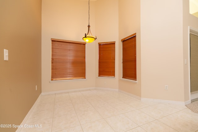 tiled empty room with a high ceiling and baseboards