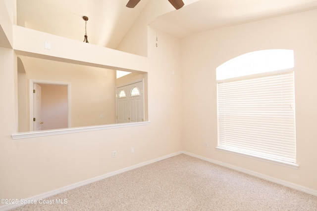 carpeted empty room with baseboards, a ceiling fan, and vaulted ceiling