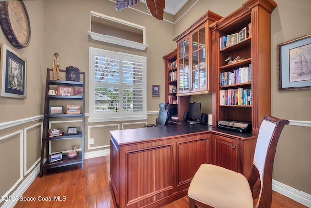 office space featuring a wainscoted wall, wood-type flooring, and a decorative wall