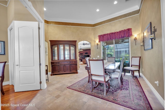 dining room featuring a ceiling fan, baseboards, recessed lighting, ornamental molding, and a towering ceiling